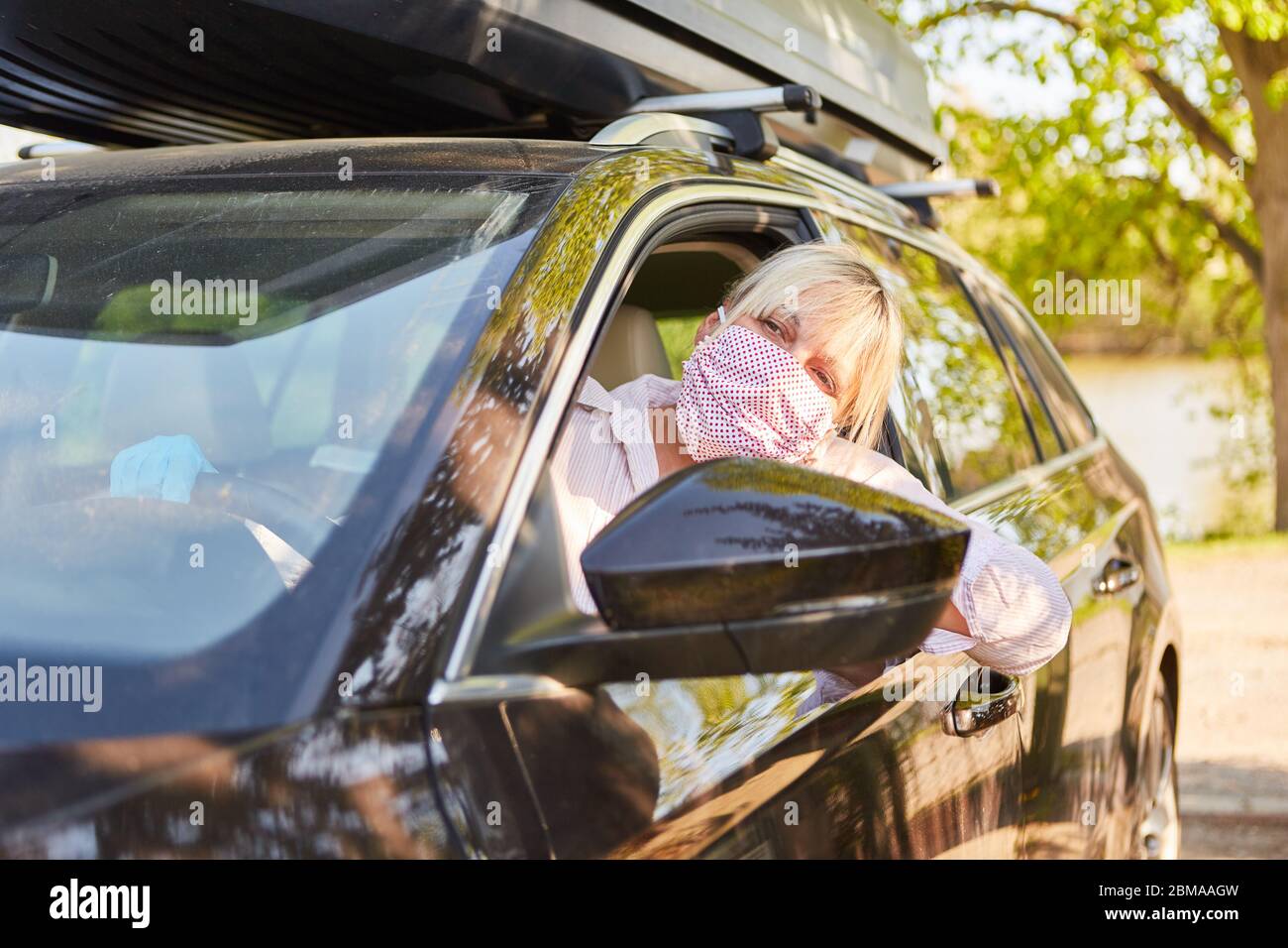 Elderly woman with face mask while driving car for corona virus home visit Stock Photo
