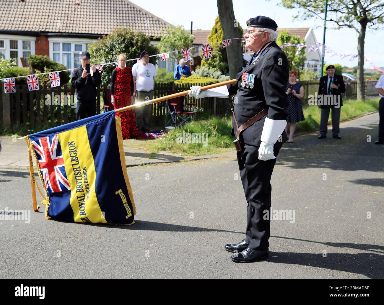 A Royal British Legion standard bearer lowers his standard in respect