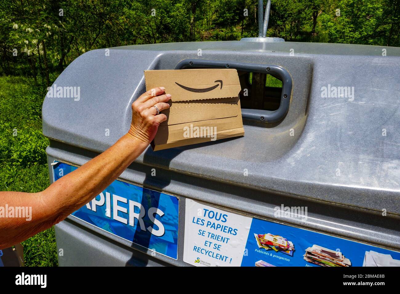 Amazon cardboard packaging being placed in large plastic recycling bin in the Ariege region of southern France Stock Photo