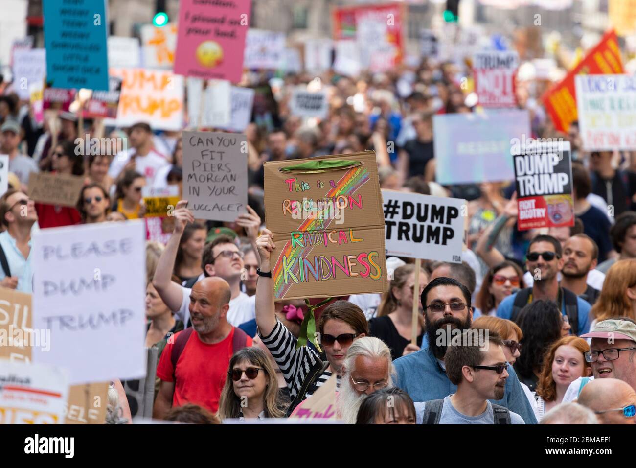 A woman holding up a sign reading 'This is a Revolution of Radical Kindness' at the protest and demonstration against Donald Trump's visit to London Stock Photo