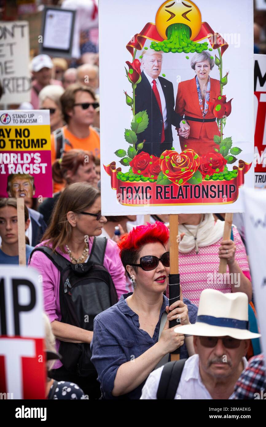 A woman holding up a sign with an image of Donald Trump and Theresa May and text reading 'Toxic Relationship' at a protest in London, 13 July 2018 Stock Photo