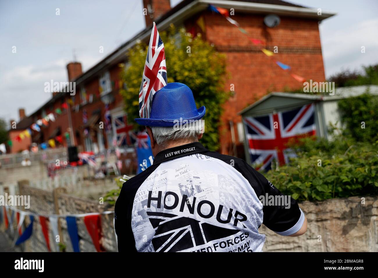 Loughborough, Leicestershire, UK. 8th May 2020. Mick Wells hangs up bunting before the two minutes silence as the nation marks the 75th anniversary of VE day during the coronavirus pandemic lockdown. Credit Darren Staples/Alamy Live News. Stock Photo