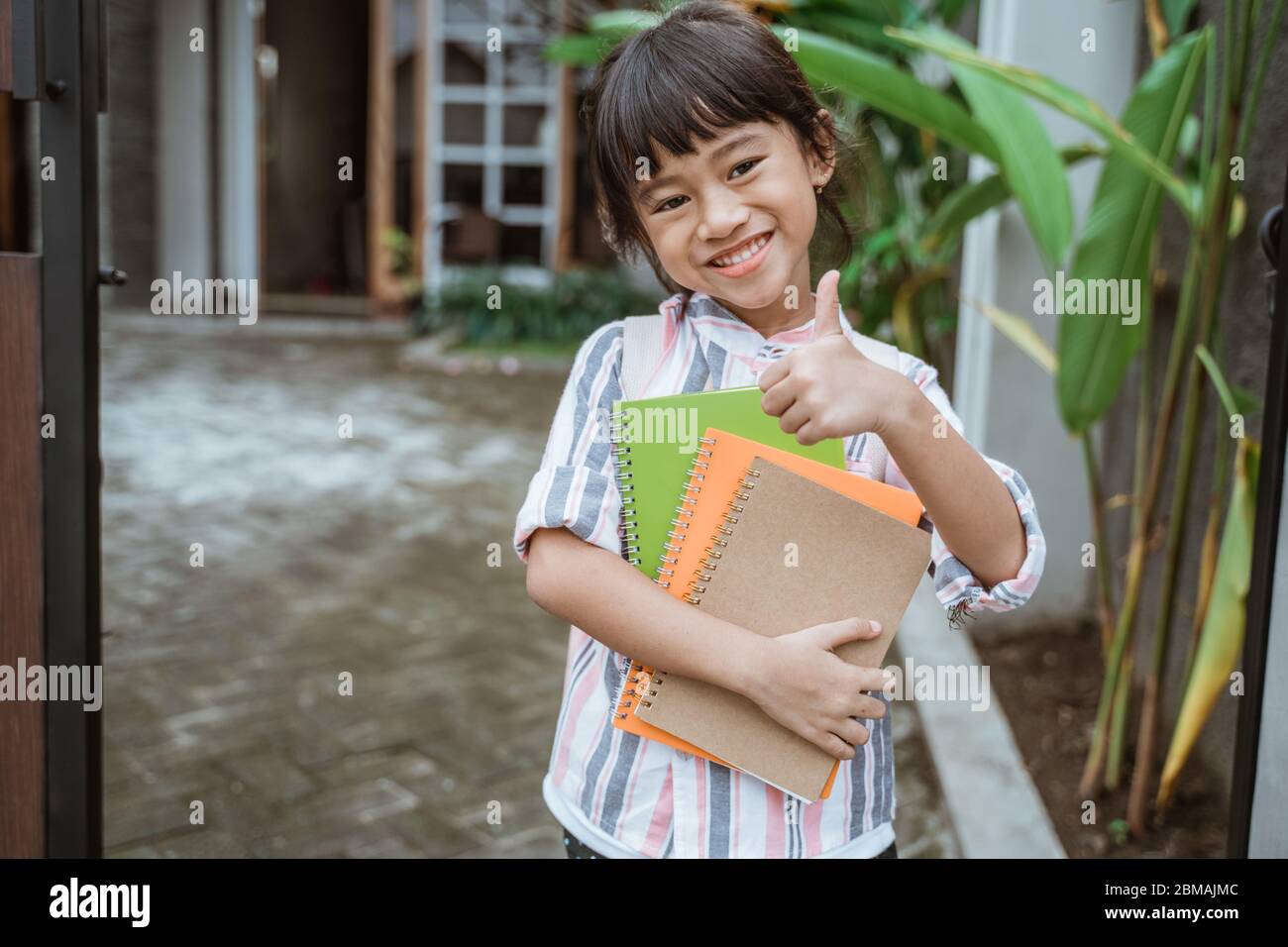 young kid student showing thumb up smiling to camera Stock Photo - Alamy
