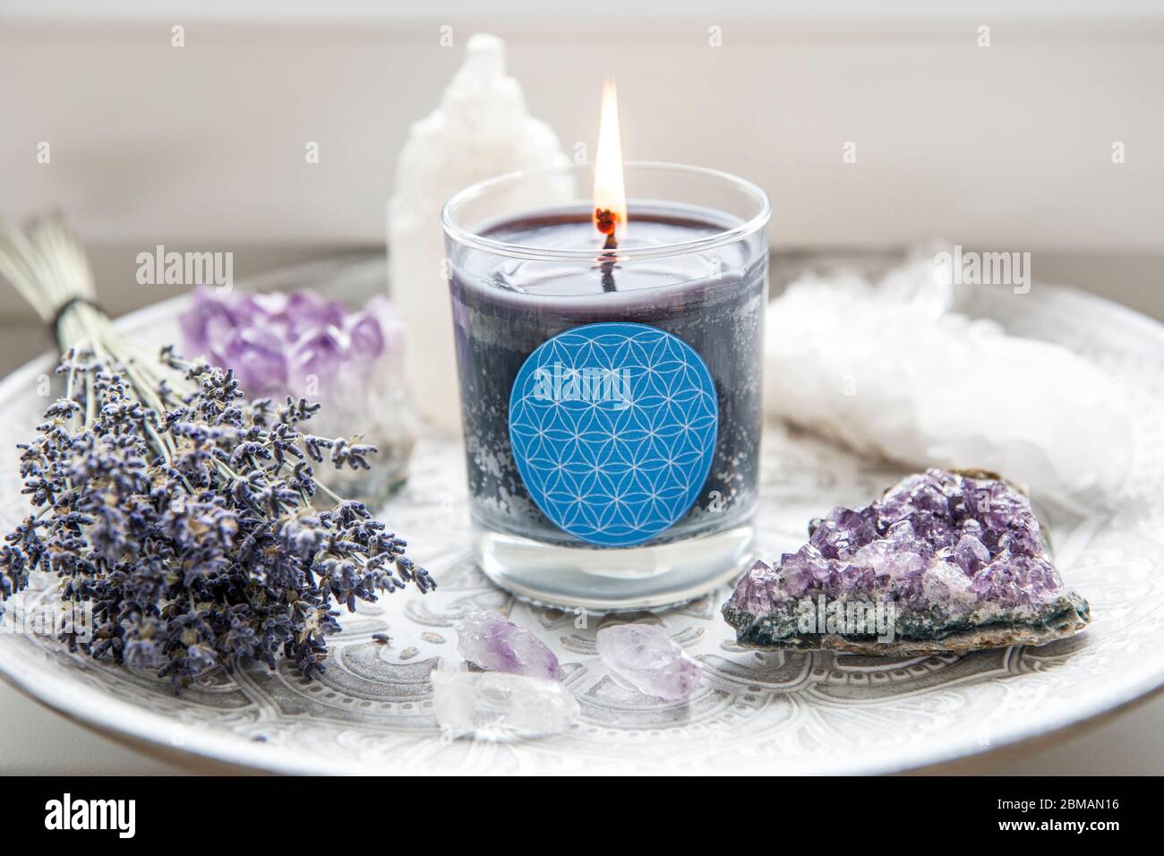Burning glass candle with homemade sign showing Flower of Life symbol