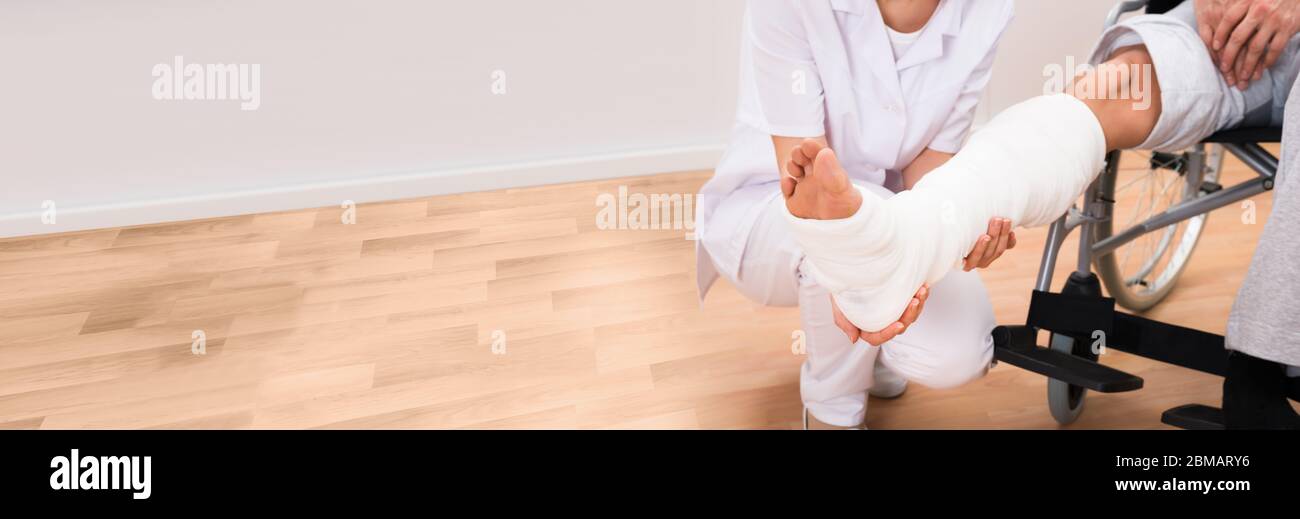 Doctor Looking At Patient Leg Cast With Broken Bone Injury Stock Photo