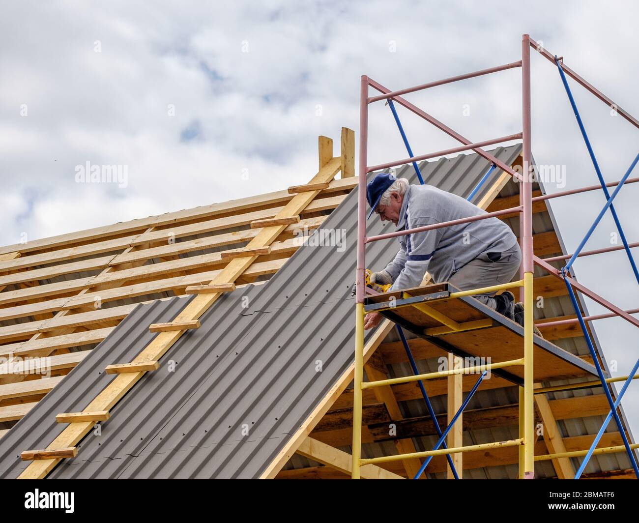 Senior grayhaired Construction man using a screwdriver, fastens a