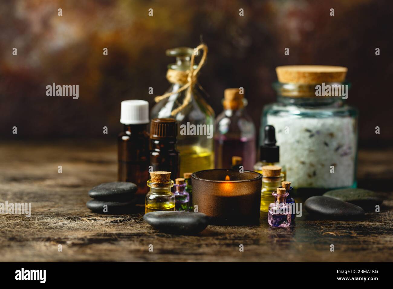 Glass bottles aroma oil, zen stones, aroma salt, candles on wooden table. Spa Treatment Stock Photo