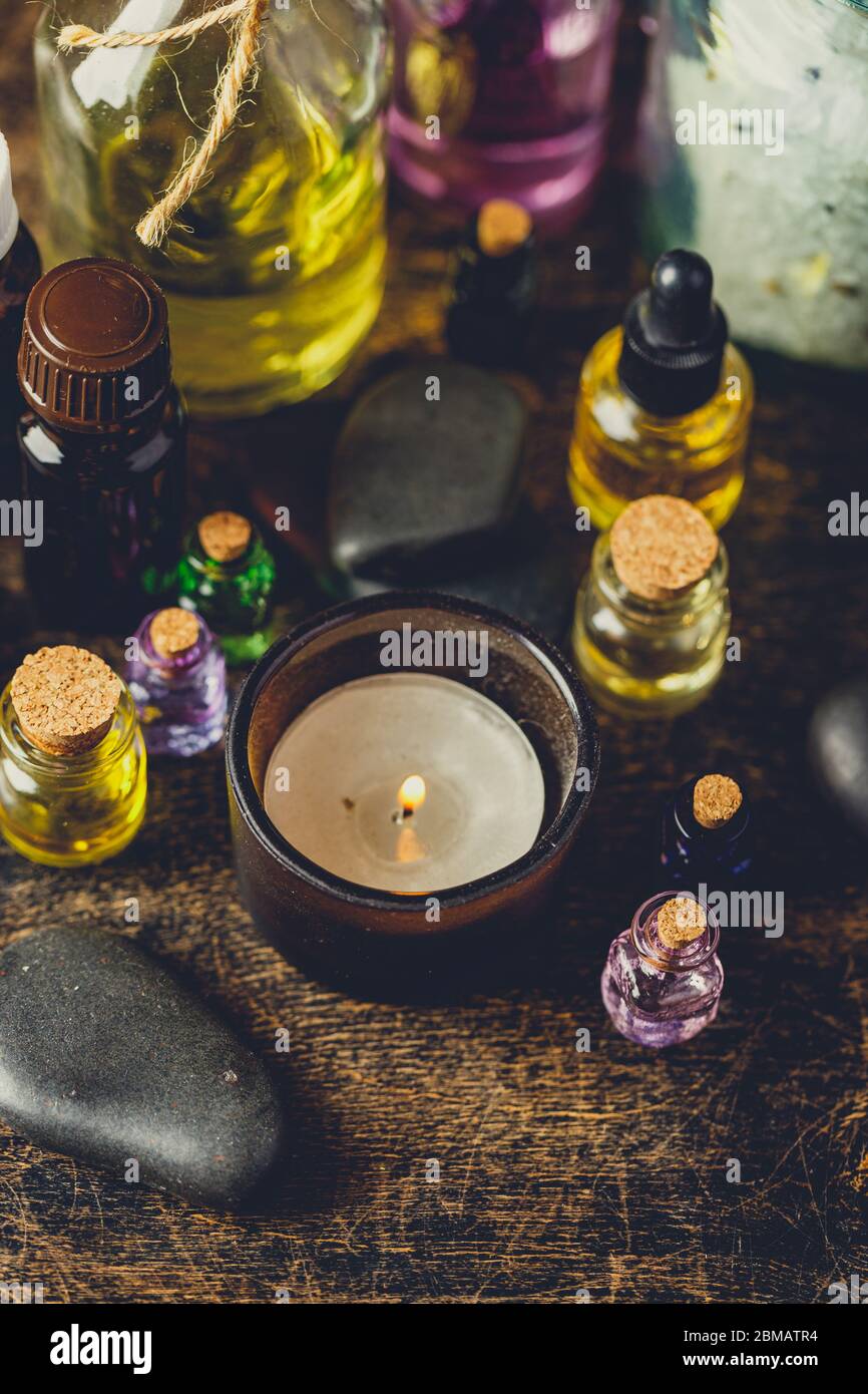 Glass bottles aroma oil, zen stones, aroma salt, candles on wooden table. Spa Treatment Stock Photo