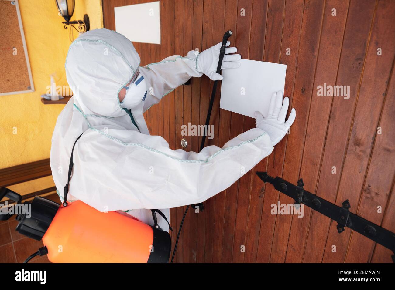 Coronavirus Pandemic. A disinfector in a protective suit and mask sprays disinfectants in house or office. Protection against COVID-19 disease. Prevention of spreding pneumonia virus with surfaces. Stock Photo