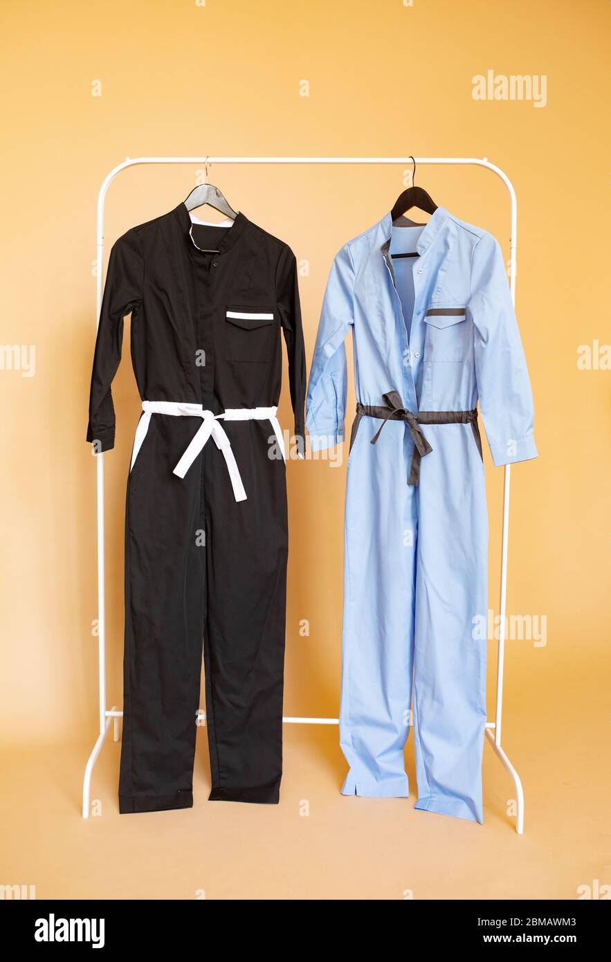Two overalls for medical workers are on a rack hanger on an orange background. Stock Photo
