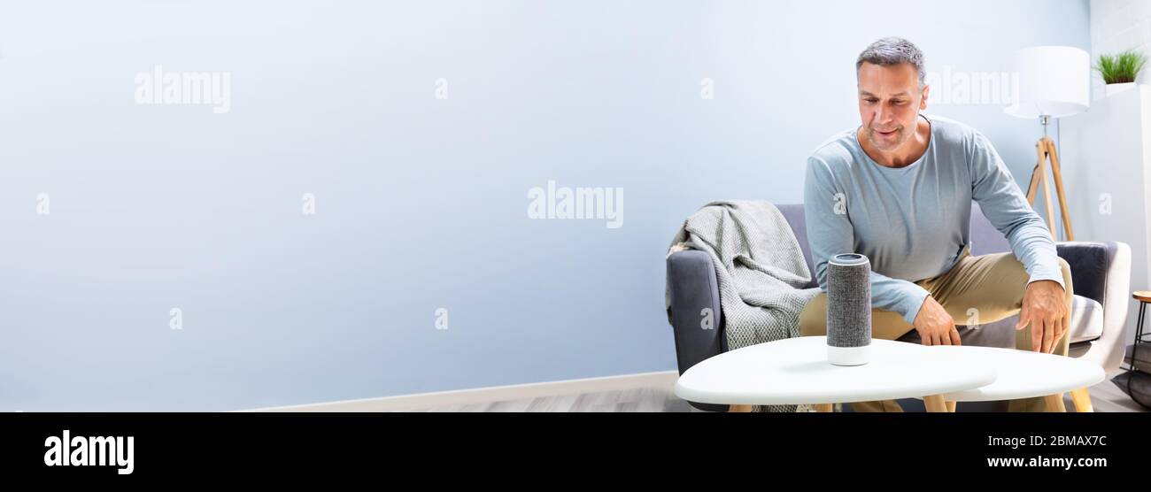 Senior Man Using Smart Home Speaker And Voice Assistant Stock Photo