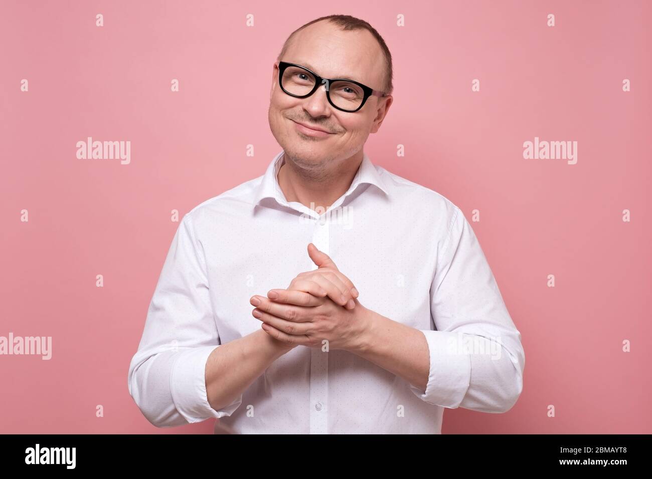 Smiling mature man in glasses and white shirt standing looking at camera Stock Photo