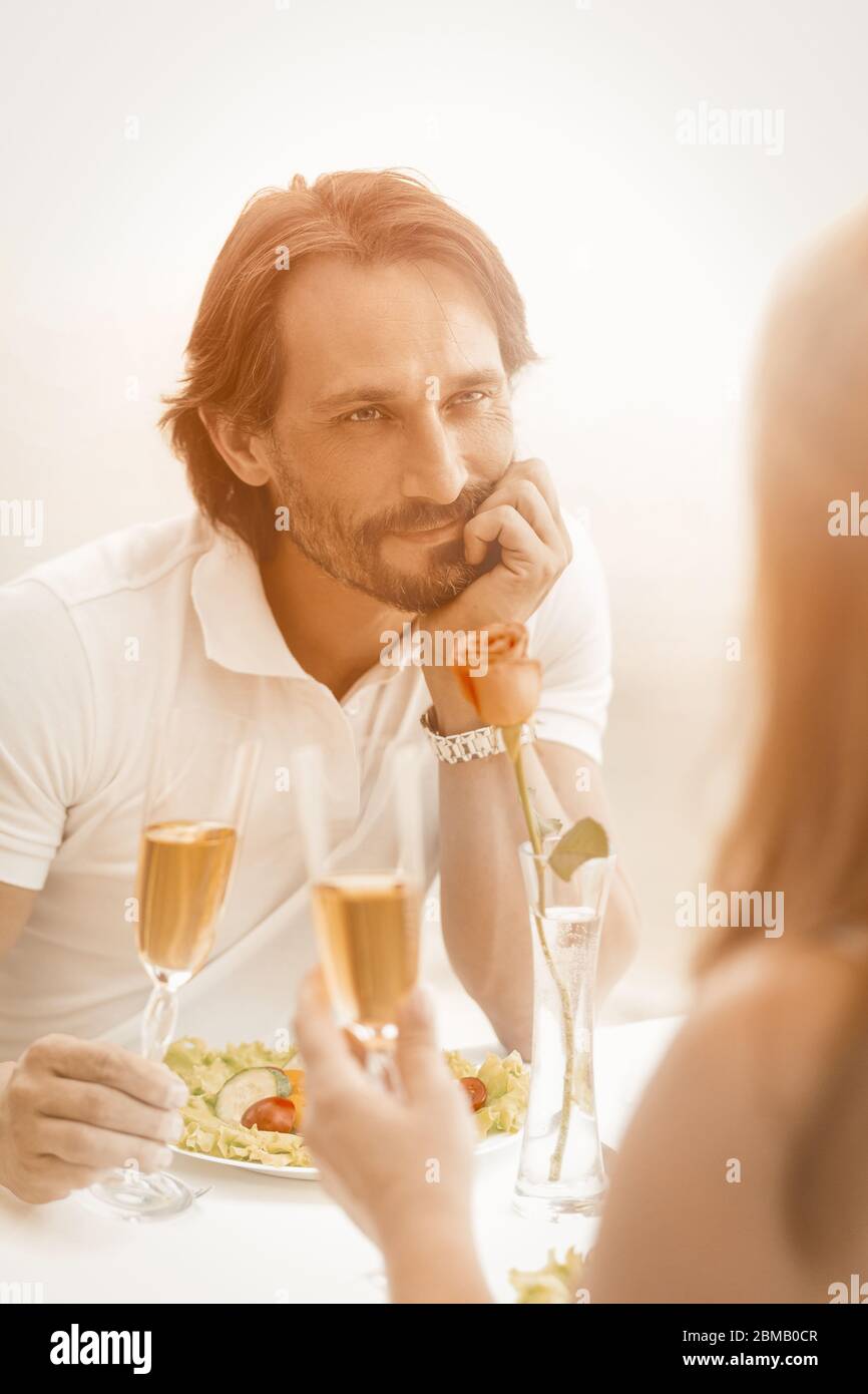 Man in love looks at his woman happily. Happy mature couple celebrating event or date at cafe on the sea coast outdoors. Toned image Stock Photo
