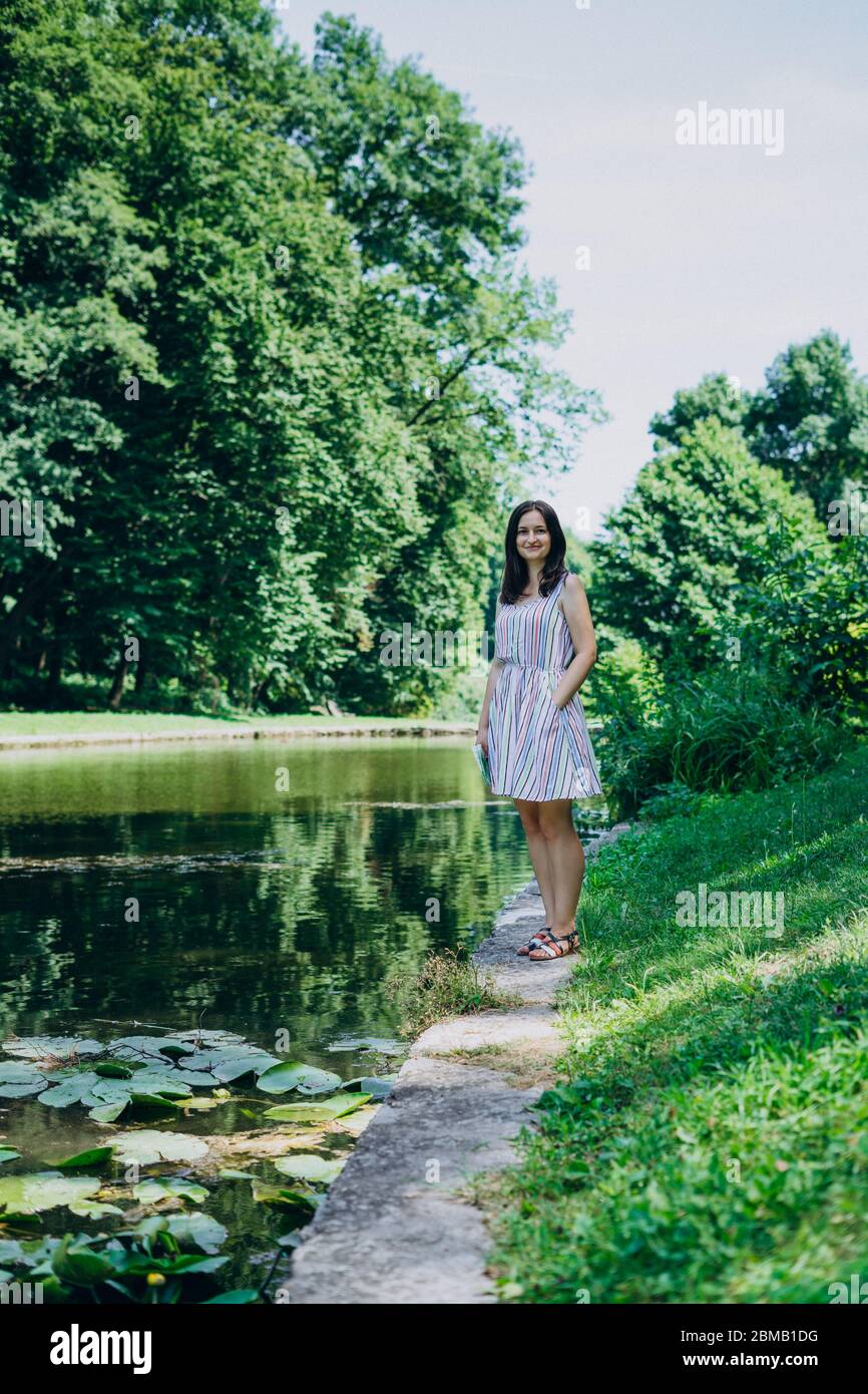 Young woman walking in the summer park. Woman in a green park near the ...