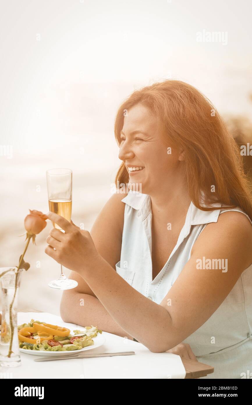 Happy woman smiles raising a glass of wine or champagne against the ...