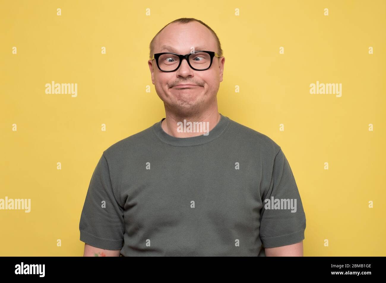 Crazy looking man in glasses making funny faces squinting eyes Stock Photo
