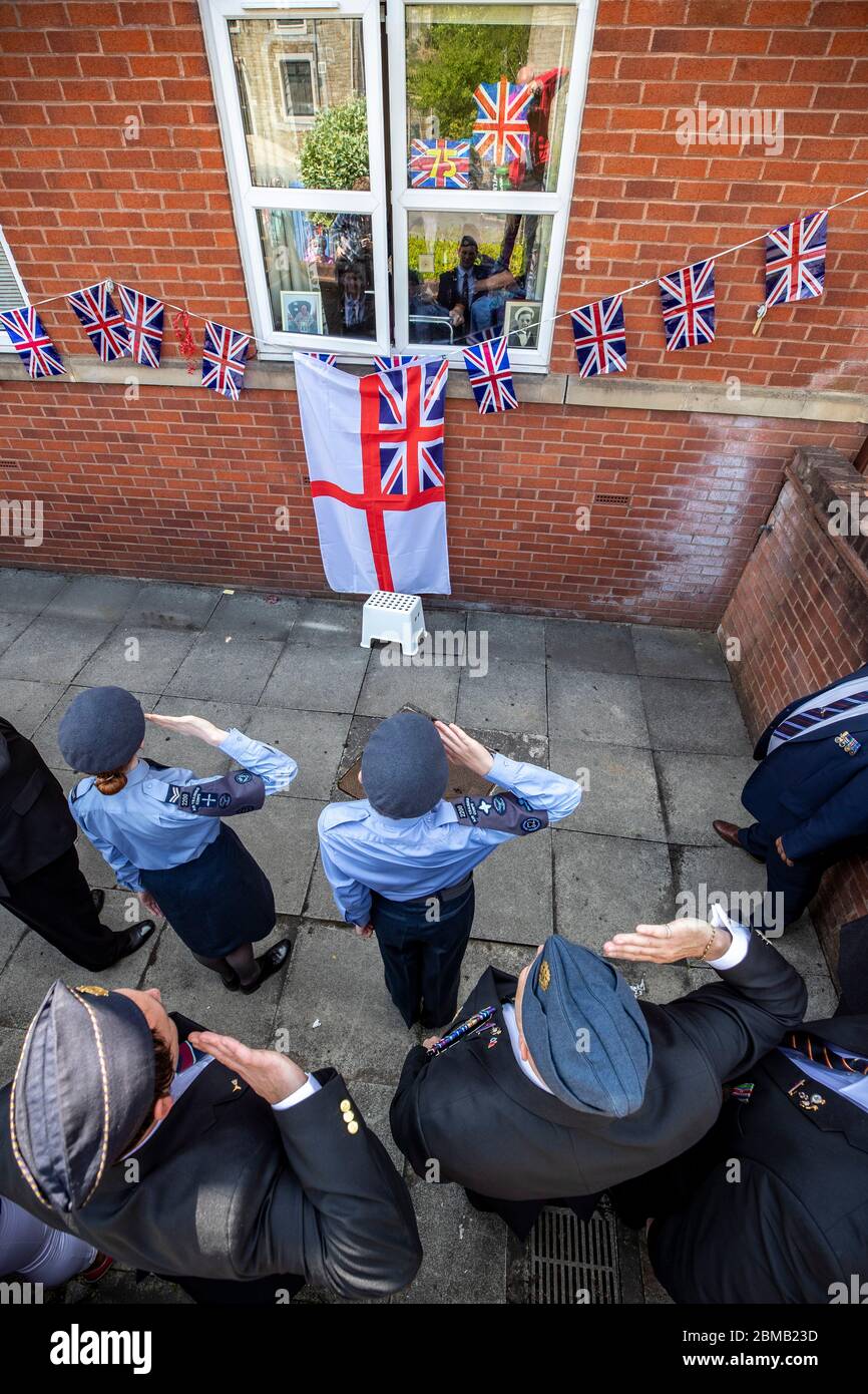 Cadets salute 95 year old Second World War veteran Signalman Eric Bradshaw, who is in isolation after testing positive for covid 19, outside Anchor's Millfield care home in Oldham, Greater Manchester, during a day of events to mark the 75th anniversary of VE Day. Stock Photo