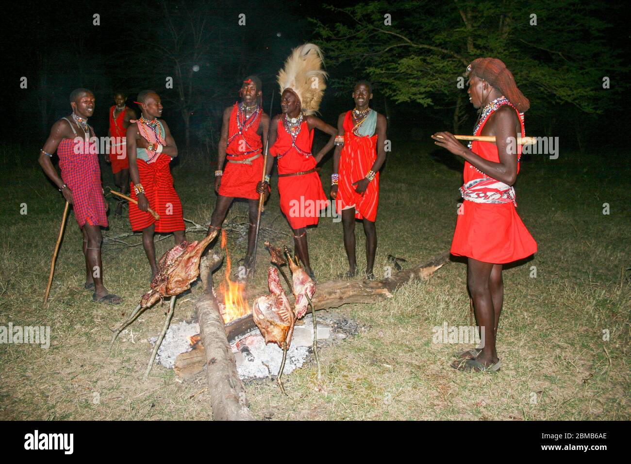 Kenya, Masai Mara, Masai (Also Maasai) Tribesman cooks meat on an open fire Stock Photo