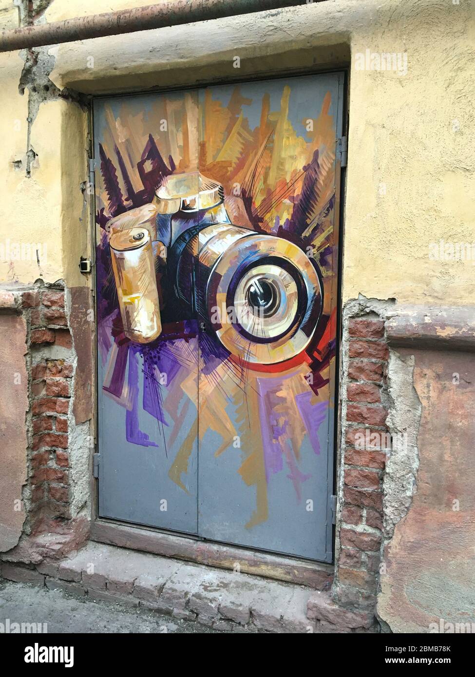 Graffiti on the wall. The image of the camera. Drawing on the whole door. Old city. Stock Photo