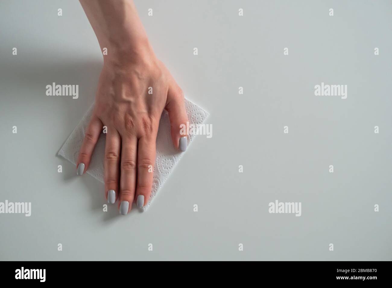 Woman hand cleaning white dining table with disinfectant wet wipe