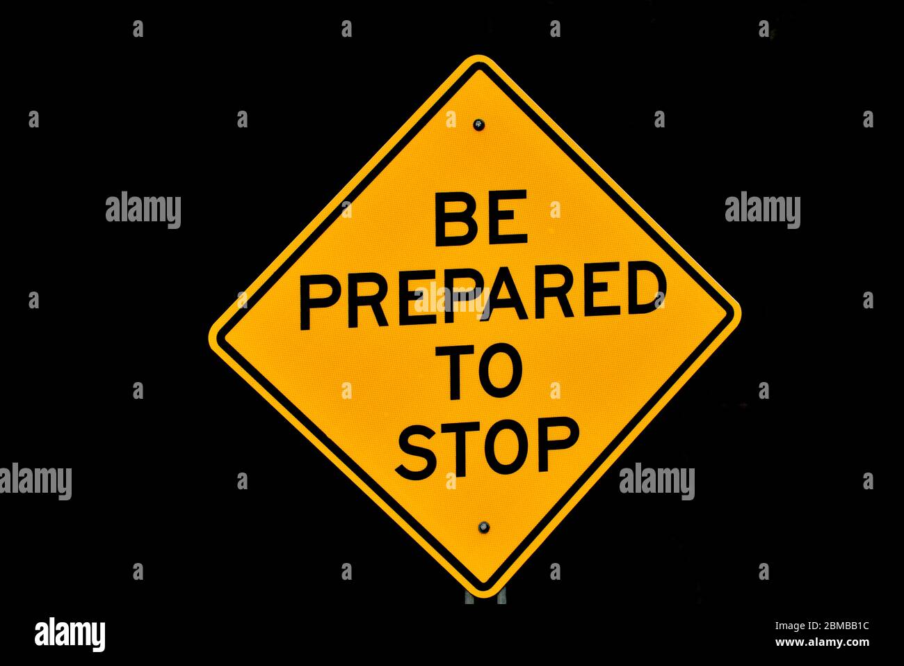 A yellow and black road sign warning drivers there is a stop ahead. Stock Photo