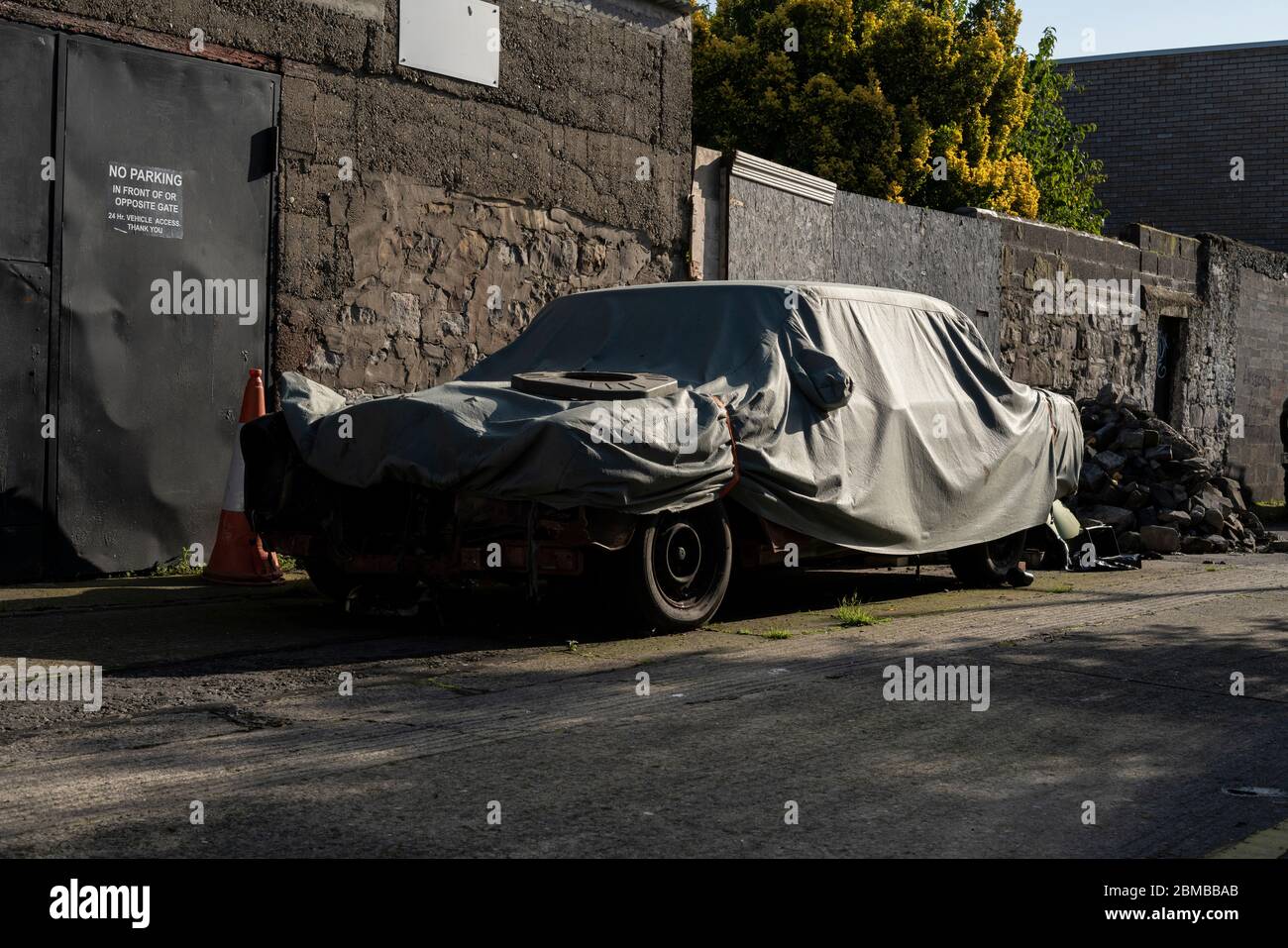 An old car under a cover in a street. Stock Photo