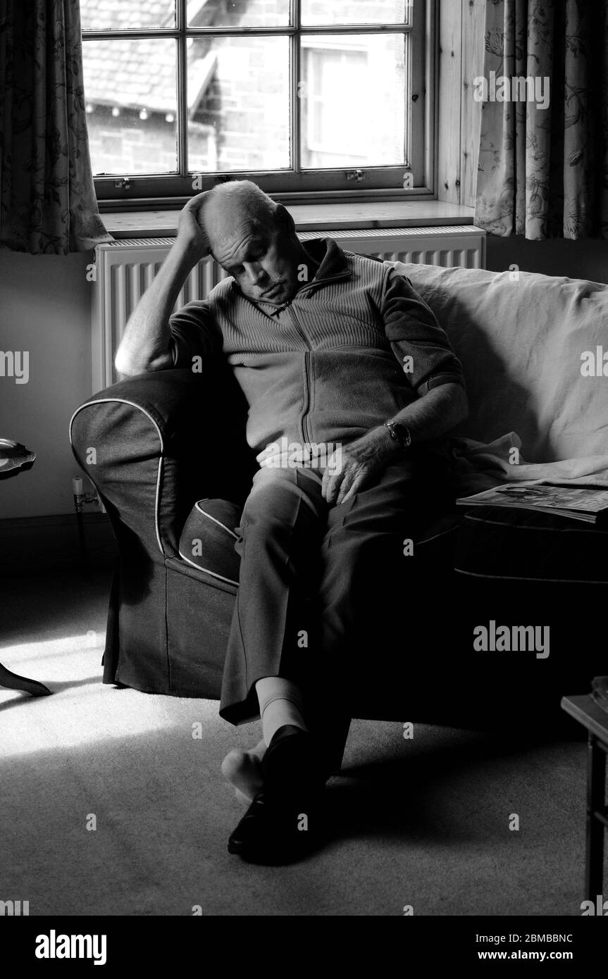 Elderly man taking an afternoon nap on a sofa Stock Photo