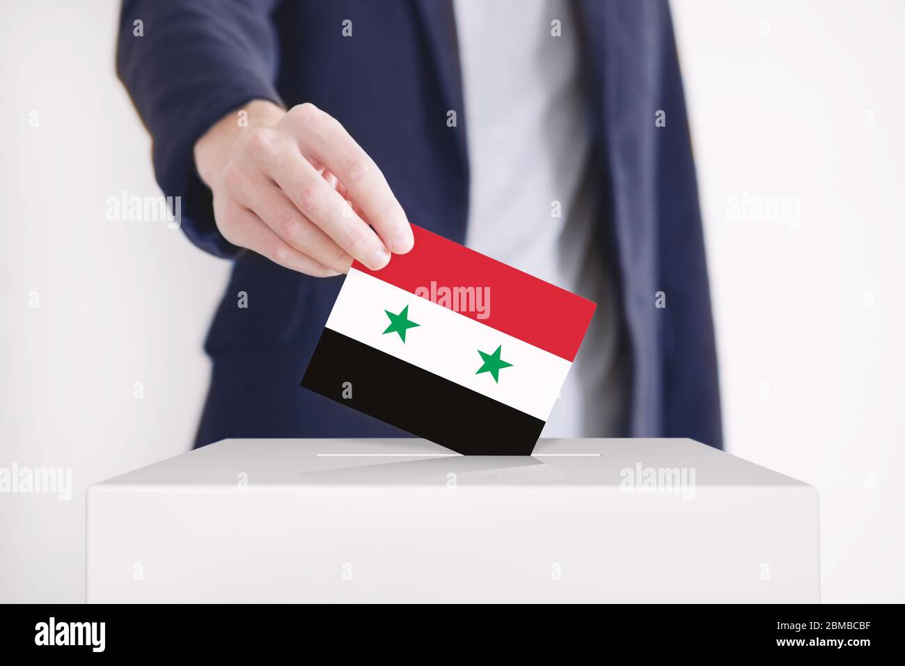Man putting a ballot with Syrian flag into a voting box. Stock Photo