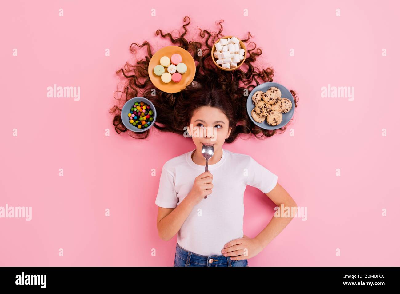 Top view above high angle flat lay flatlay lie concept portrait of nice lovely funny cheery hungry wavy-haired girl licking lip meal dish snack on Stock Photo