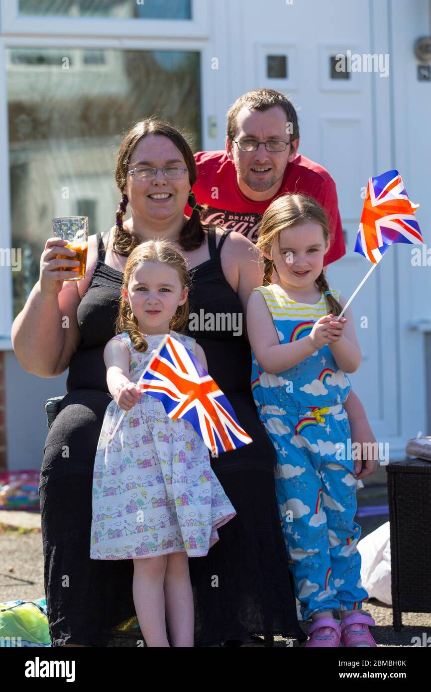 Ashford, Kent, UK. 8th May, 2020. Members of the community in the village of Hamstreet near Ashford in Kent come together to commemorate VE day on it's 75th anniversary with a tea party outside their front garden. Families outside there houses pose for pictures with union jack flags. ©Paul Lawrenson 2020, Photo Credit: Paul Lawrenson/Alamy Live News Stock Photo