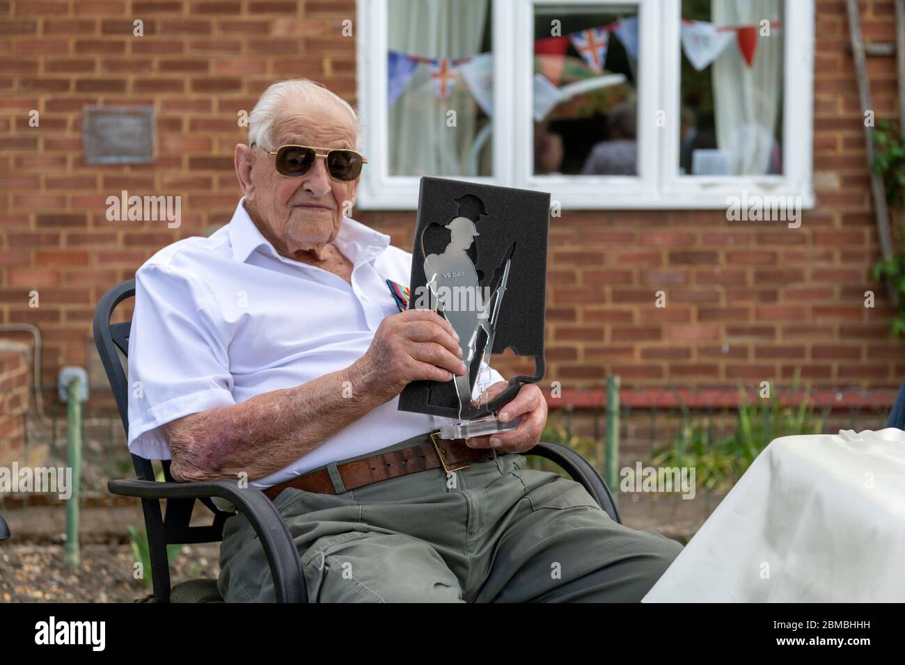Over, Cambridgeshire, UK. 8th May, 2020. WWII Veteran Cyril Cook, enjoys a garden party at his home to celebrate the 75th Anniversary of VE Day. Aged 98 years he was a Private in the Royal Electrical and Mechanical Engineers. He was presented with a plague and certificate by the local branch of the British Legion and joined by members of his family. Credit: Julian Eales/Alamy Live News Stock Photo