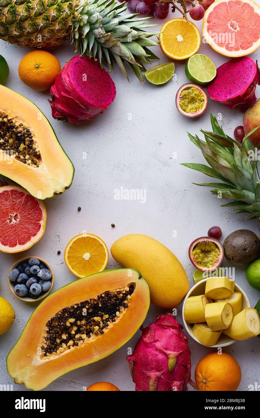 Flat lay tropical exotic fruits with copy space. Healthy summer food ingredients: papaya, pitaya, pineapple, orange, lime, grapes and mango. Stock Photo