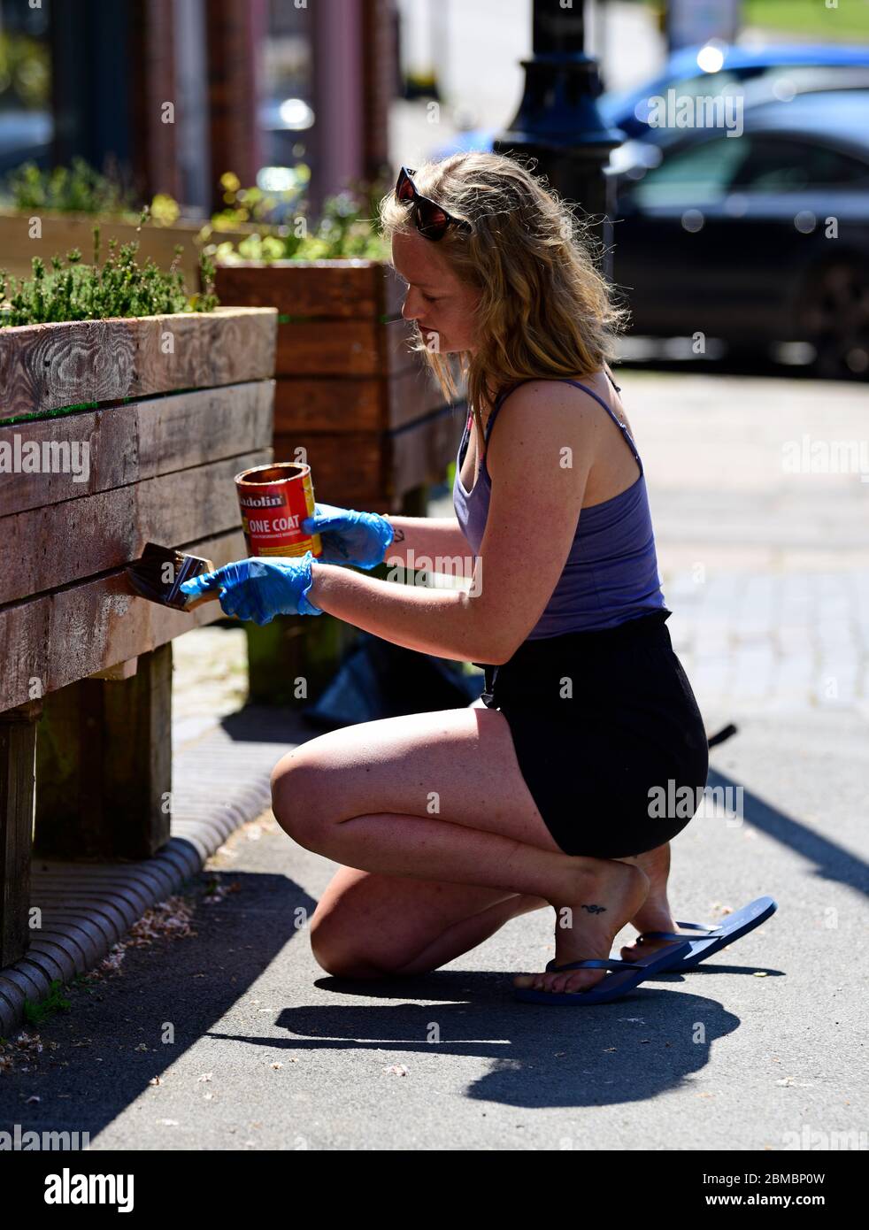Woman painting flower bed box outside her shop during Coronavirus (COVID-19) pandemic, Haslemere, Surrey, UK. Stock Photo