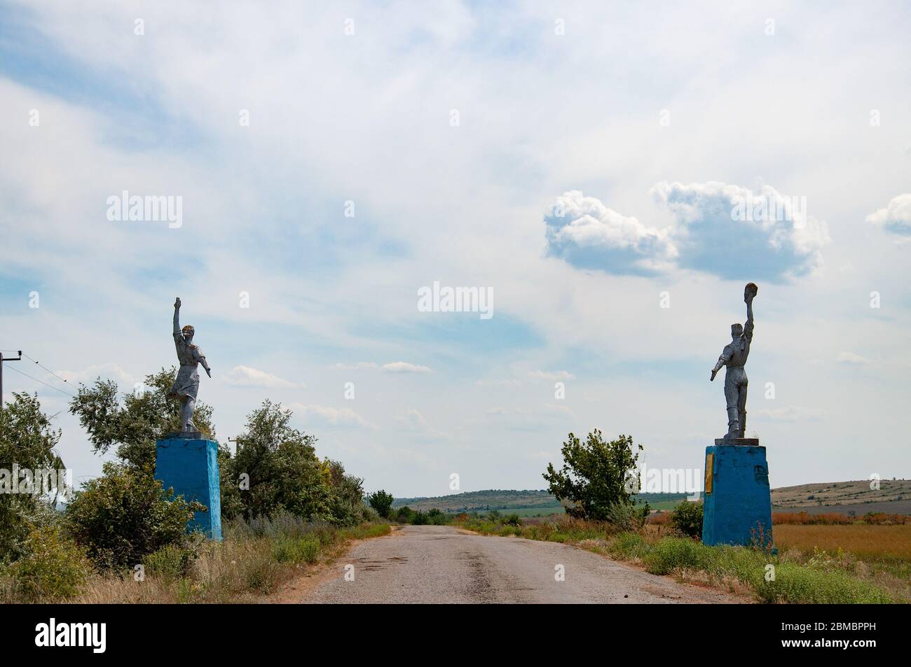 Silhouettes of Worker and Kolkhoz Woman style statues by roadsides. Social realism monuments in countryside of Ukraine. Stock Photo