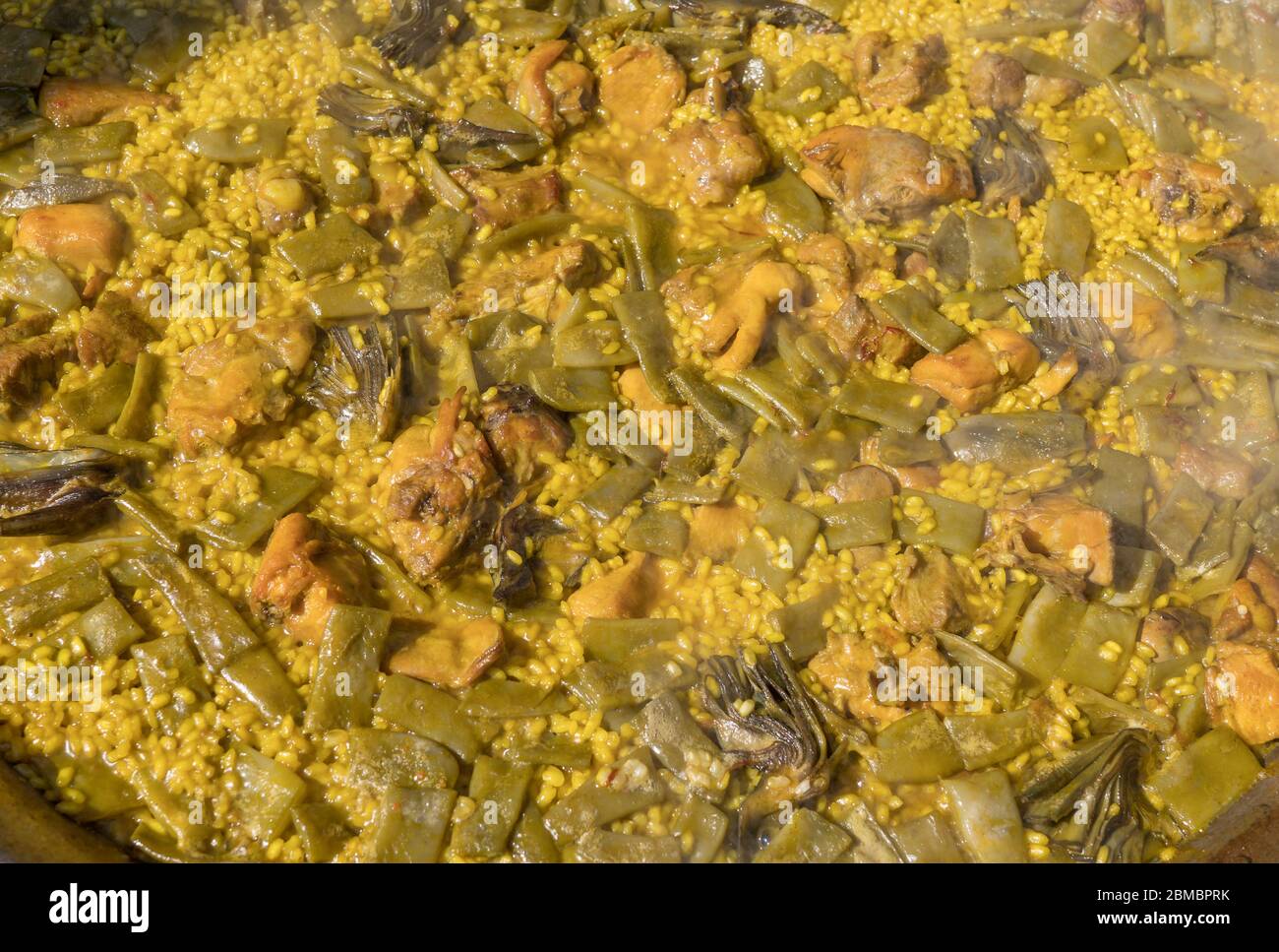 Cooking authentic Valencian paella with chicken meat, rabbit meat