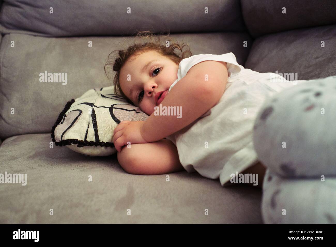little girl watches TV resting on the couch Stock Photo Alamy