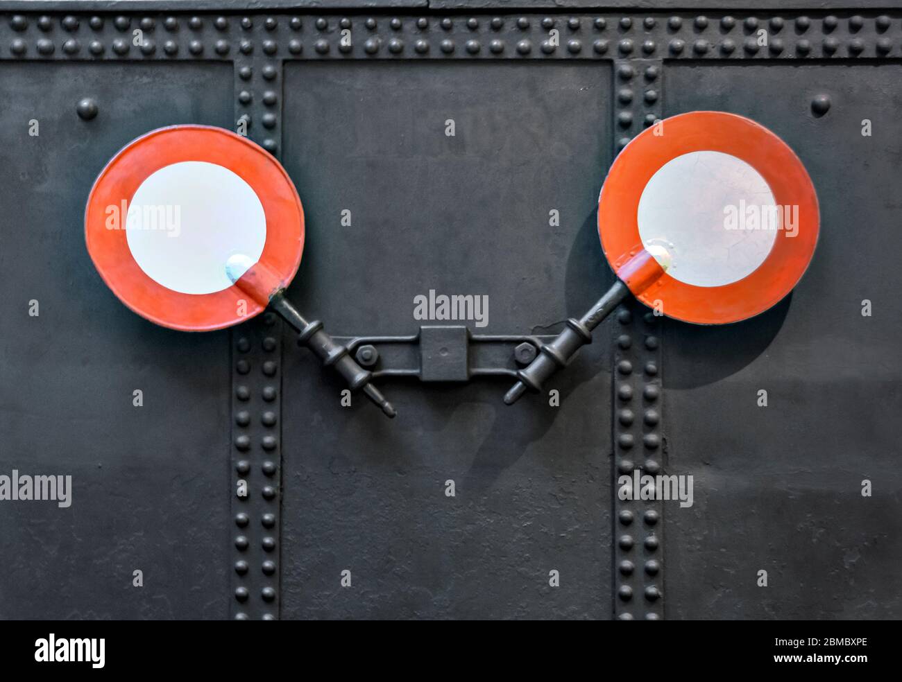 two signalling discs of the former Imperial-Royal State Railways of Austria on a black metal sheet with rivets showing the end of a train Stock Photo
