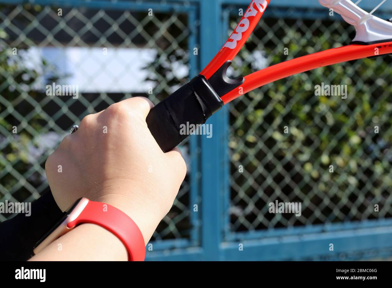 Tennis racquet with a fence of a tennis court in the background