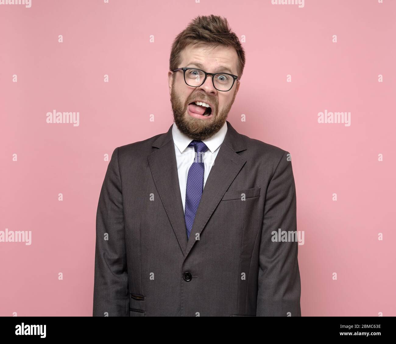 Crazy man in glasses and a suit with an open mouth and a strange expression on face. Concept of stress and mental health. Stock Photo