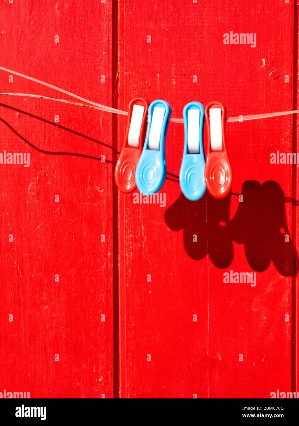 Clothesline Clips with red painted wooden on the background - Milos Island, Greece Stock Photo