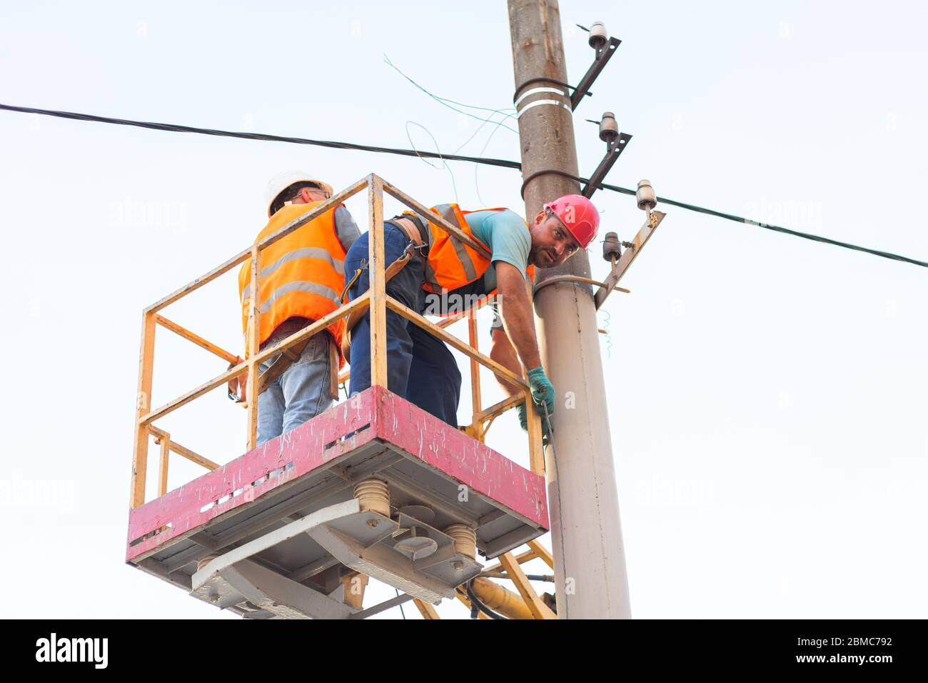 electricians on the pillars install the mount for the power line