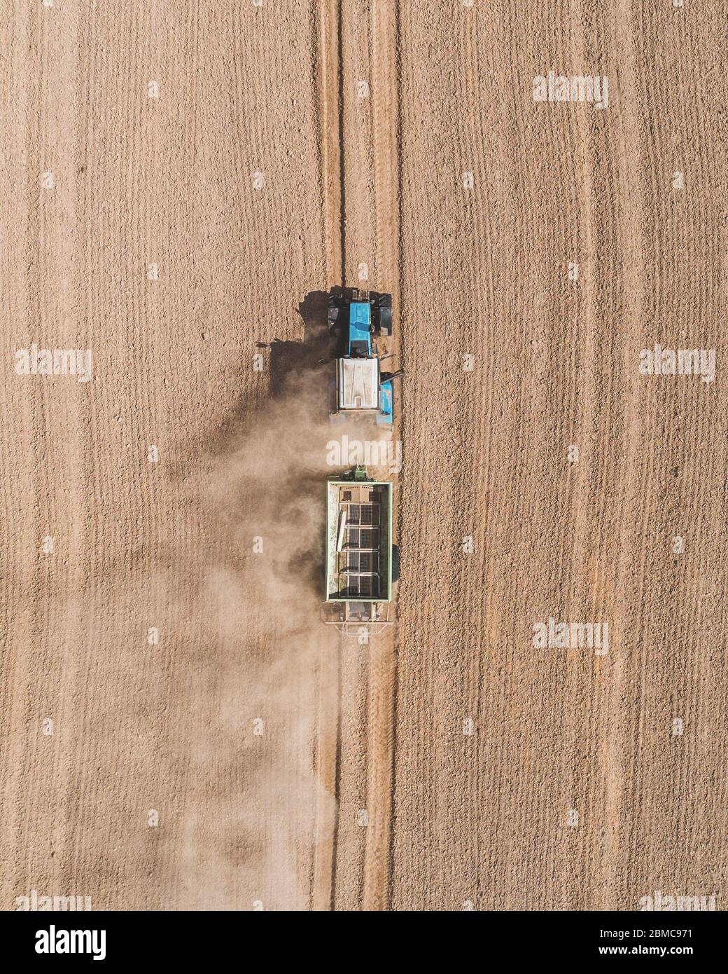 Aerial view of a blue tractor working in a field with a fertilizer and