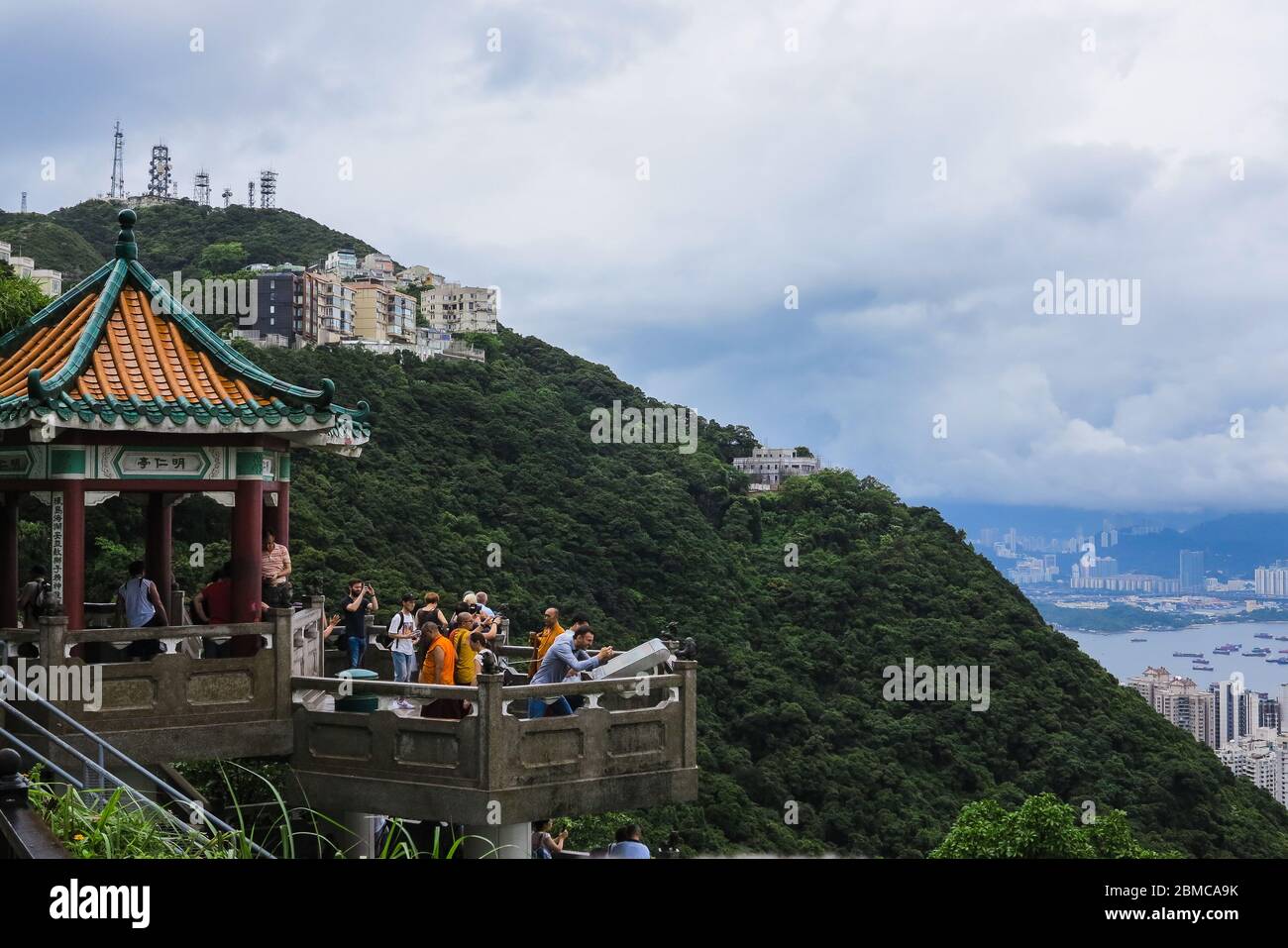 A crowd of tourists in a pagoda taking in the view of Victoria Peak, Hong Kong Stock Photo