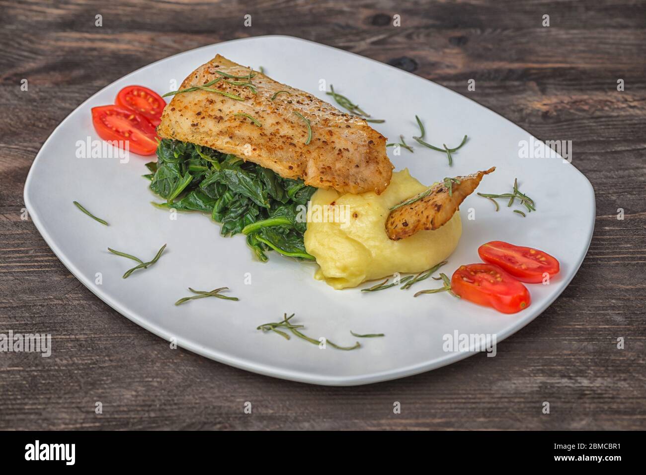 Fish hake Argentinian spinach potatoes cherry top Stock Photo