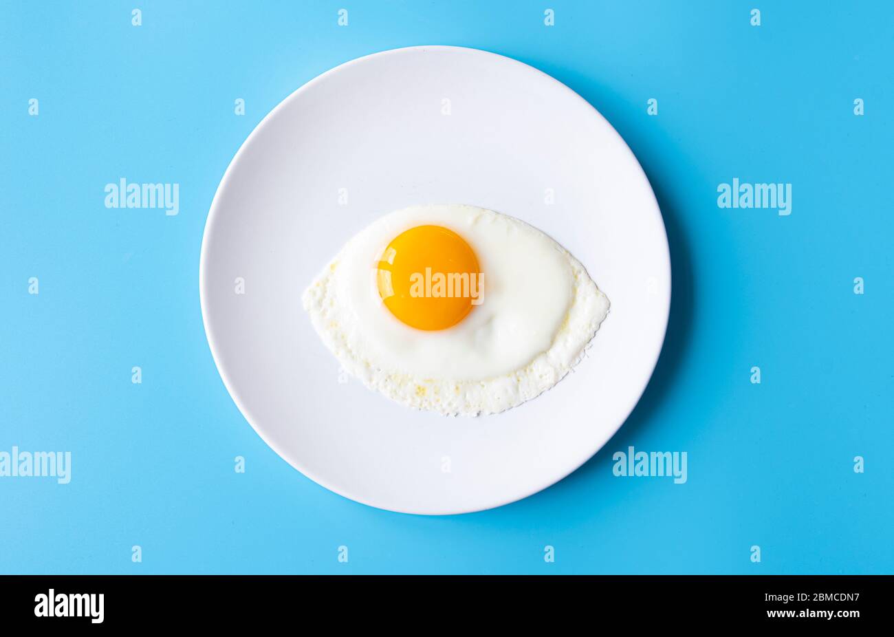 Breakfast, fried egg, yolk, omelet on white plate with color table, creative picture Stock Photo
