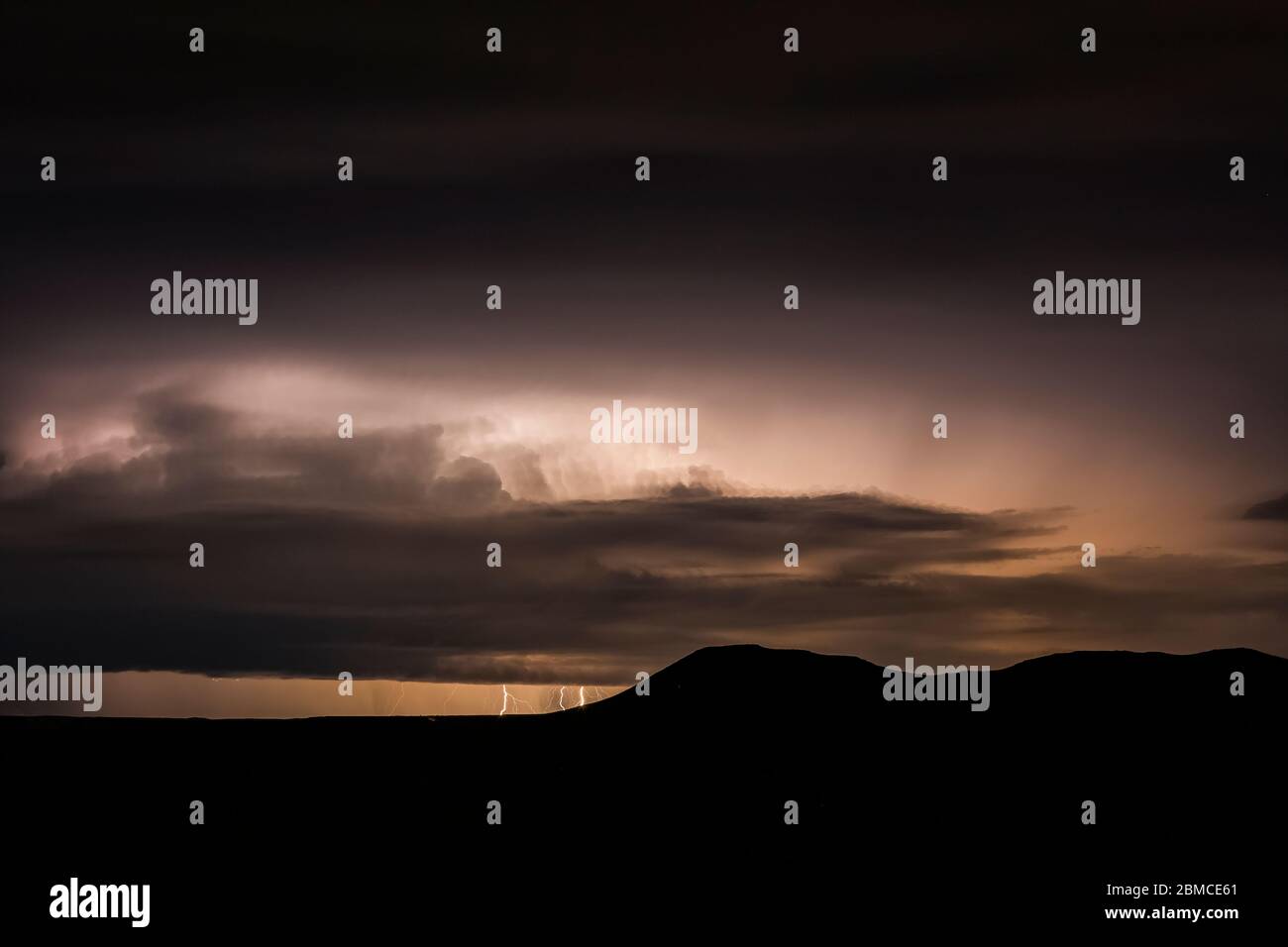 Intense nighttime thunderstorm with cloud-to-ground lightning over the Mimbres Valley and surrounding mountains, viewed from City of Rocks State Park, Stock Photo