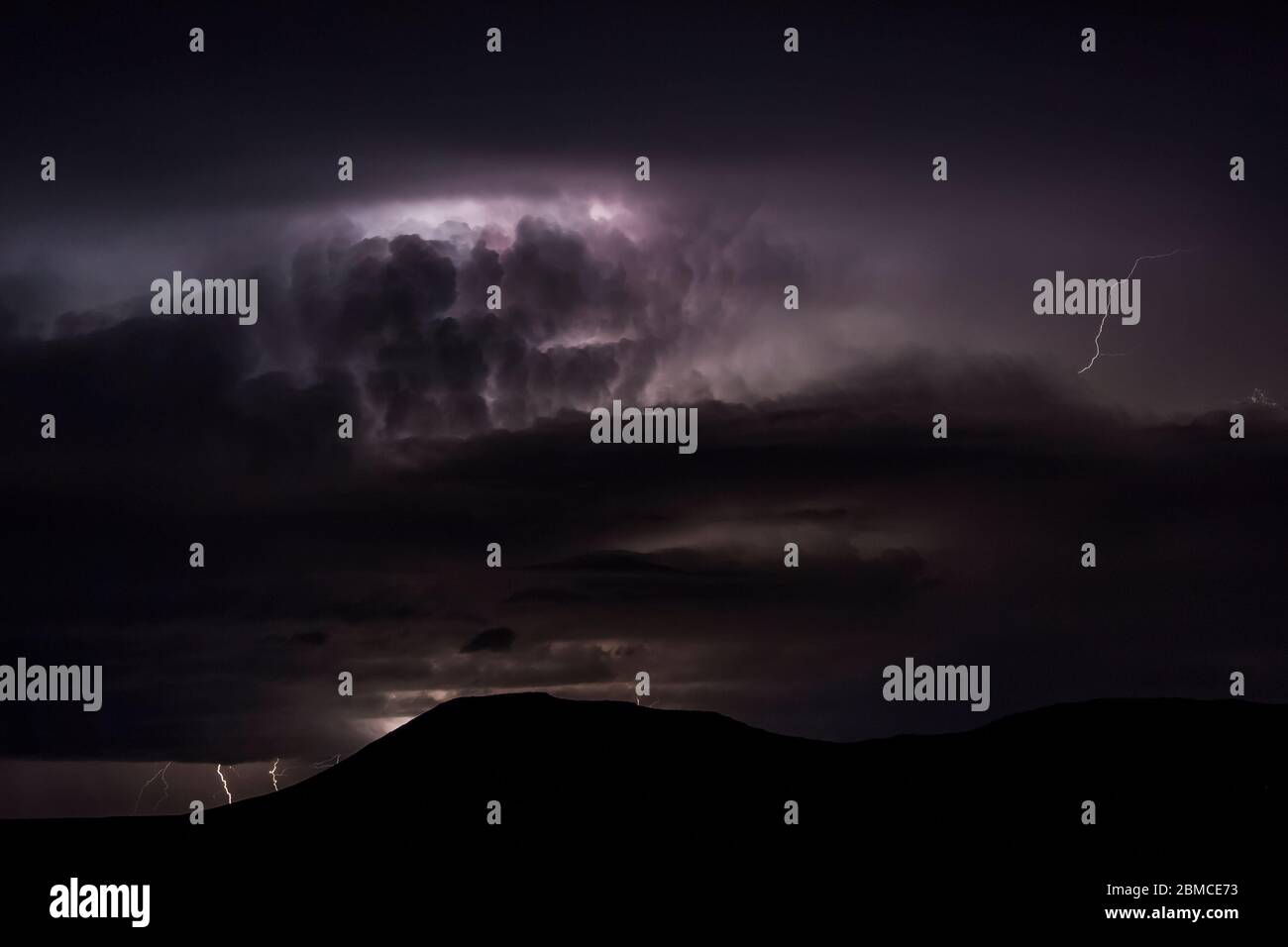 Intense nighttime thunderstorm with cloud-to-ground and intracloud lightning over the Mimbres Valley and surrounding mountains, viewed from City of Ro Stock Photo