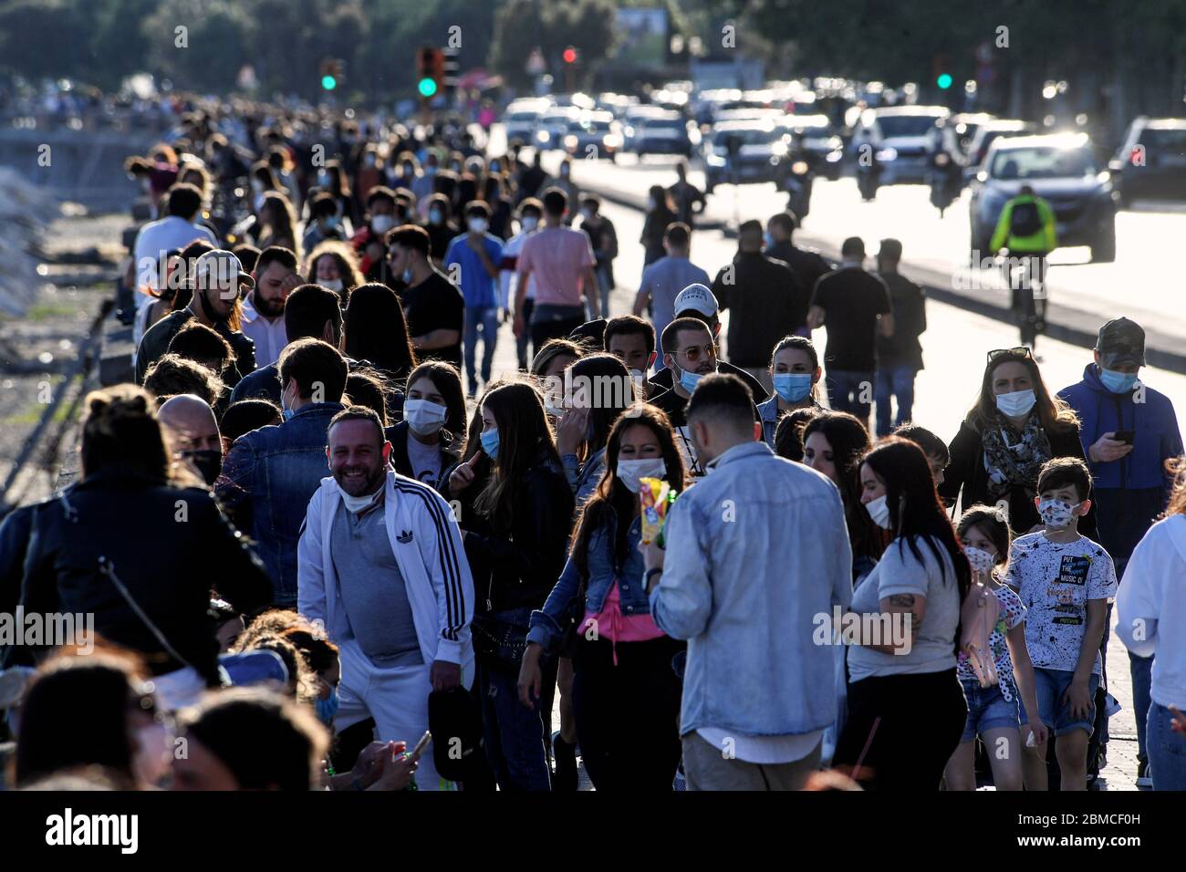 People in protective masks stroll along the Caracciolo seafront in Naples, southern Italy. The Italian government announced a gradual lifting of the lockdown restrictions that were implemented to stem the widespread of the SARS-CoV-2 coronavirus that causes the COVID-19 disease. Stock Photo