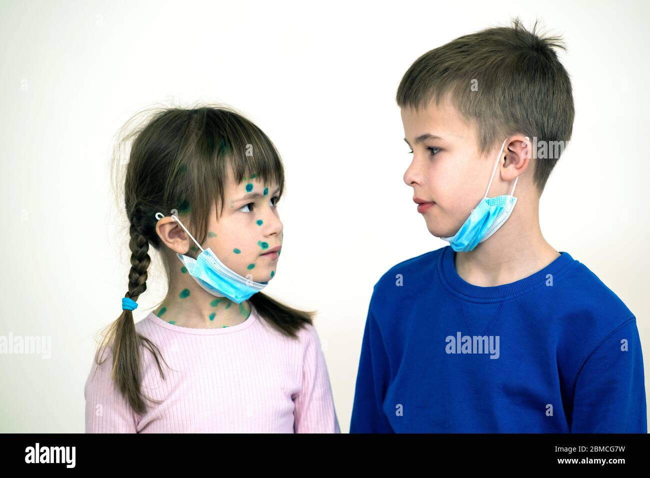 Boy and girl wearing blue protective medical mask ill with chickenpox, measles or rubella virus with rashes on body. Children protection during epidem Stock Photo