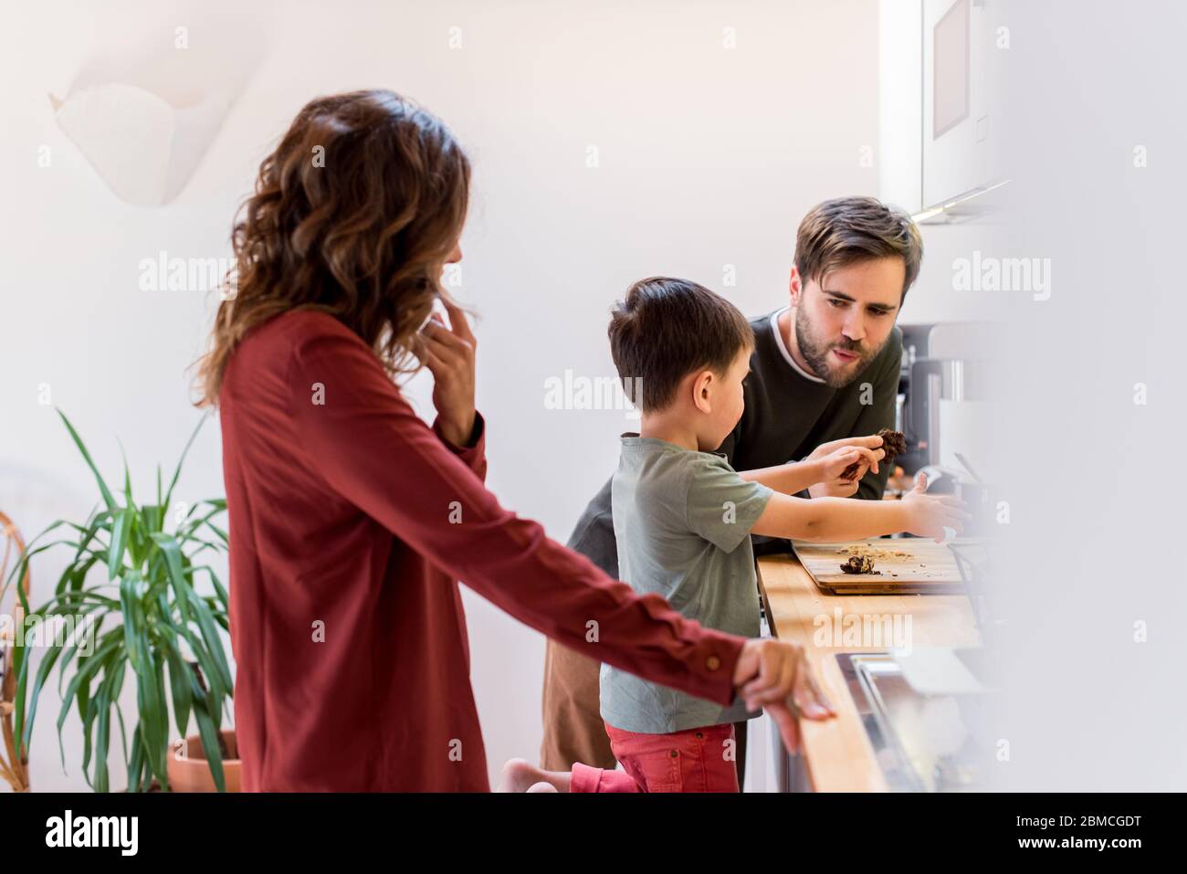Family preparing and eating peanut chocolate cookies at home Stock Photo